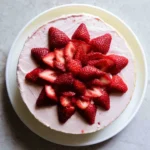 Slice of homemade strawberry cake topped with whipped cream and fresh strawberries.