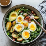 A vibrant breakfast salad topped with eggs, avocado, and fresh veggies.