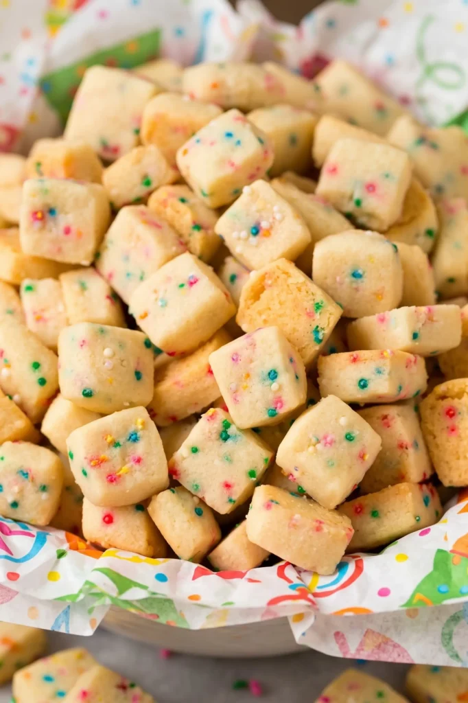 Christmas Shortbread Cookie Bites with festive sprinkles spilling from a red bowl
